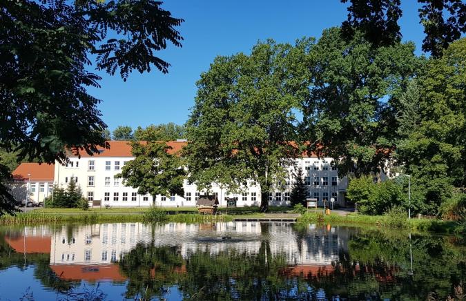 Frontansicht der Schule mit Teich
