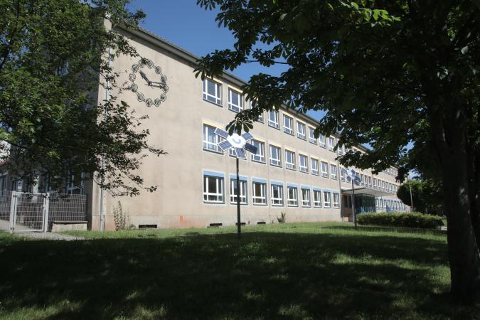 Die Heinrich-von-Kleist-Oberschule von vorn, grüne Bäume und Wiese sind zu sehen.